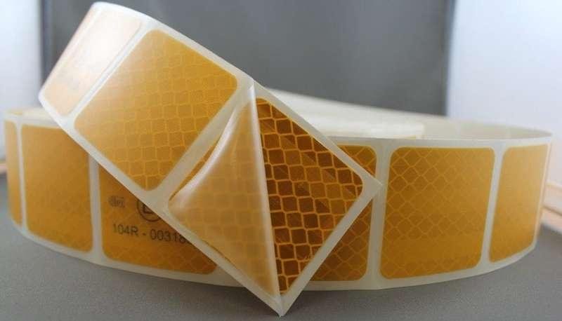 Segmented yellow reflective tape with one section peeled from the liner