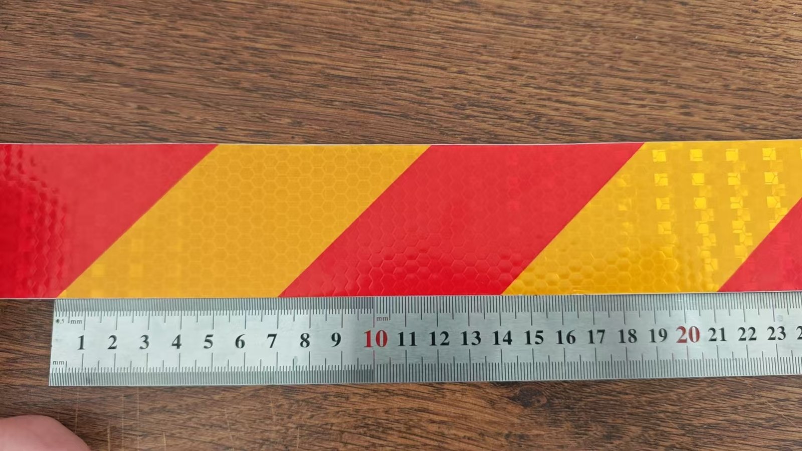 Actual red and yellow diagonal reflective tape beside a ruler for pattern spacing reference