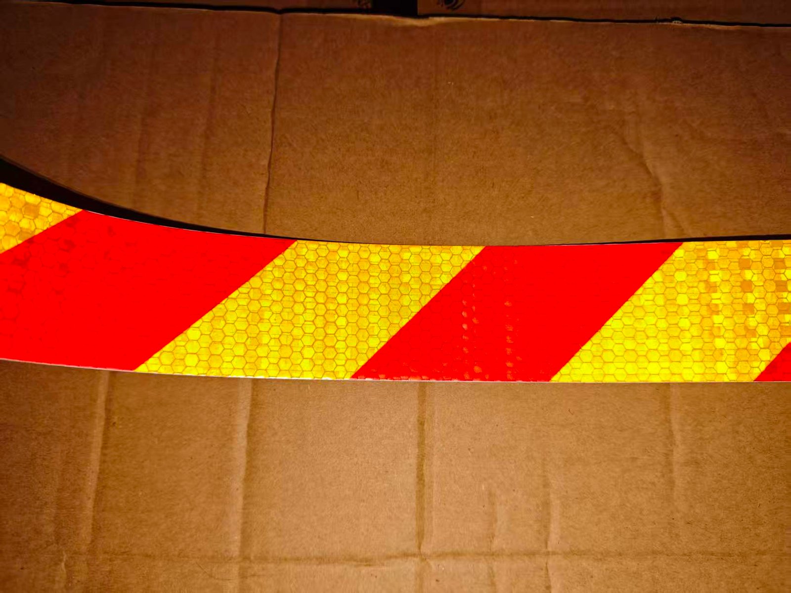 Actual illuminated red and yellow diagonal tape showing reflective appearance in both colors