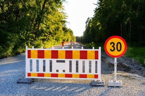 Road barrier using red and yellow strip markings beside a speed sign