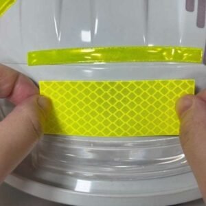 Fluorescent yellow reflective sticker being positioned on a smooth curved sample surface