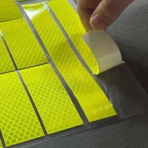 Peeling a fluorescent yellow reflective sticker from its backing