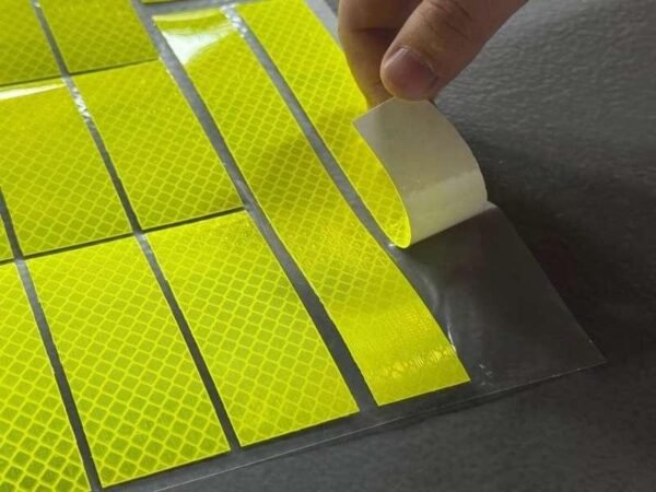 Peeling a fluorescent yellow reflective sticker from its backing