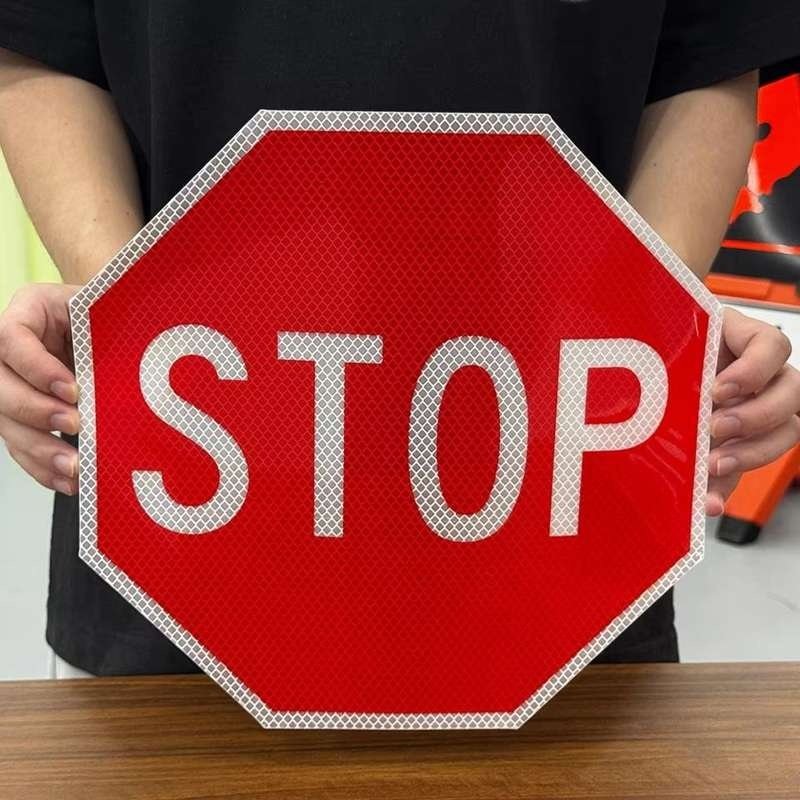 Red and white octagonal reflective STOP sign held for a front view