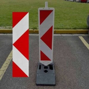 Red and white reflective panel sticker beside a freestanding road delineator