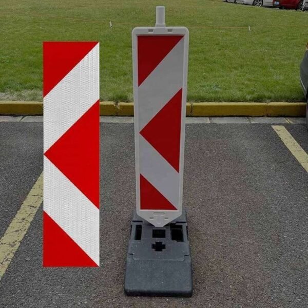 Red and white reflective panel sticker beside a freestanding road delineator