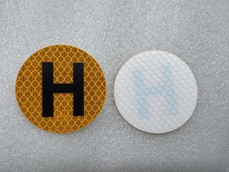 Front and white reverse of round yellow reflective H sticker