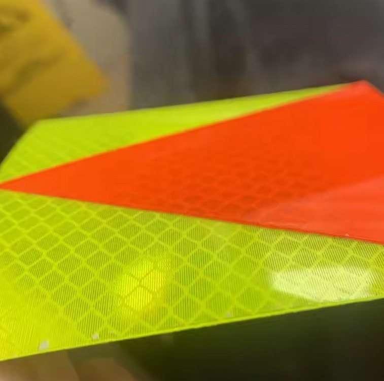Close-up of orange-red triangle on fluorescent yellow reflective material