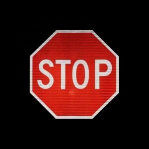Red and white reflective octagonal STOP sign against a dark background