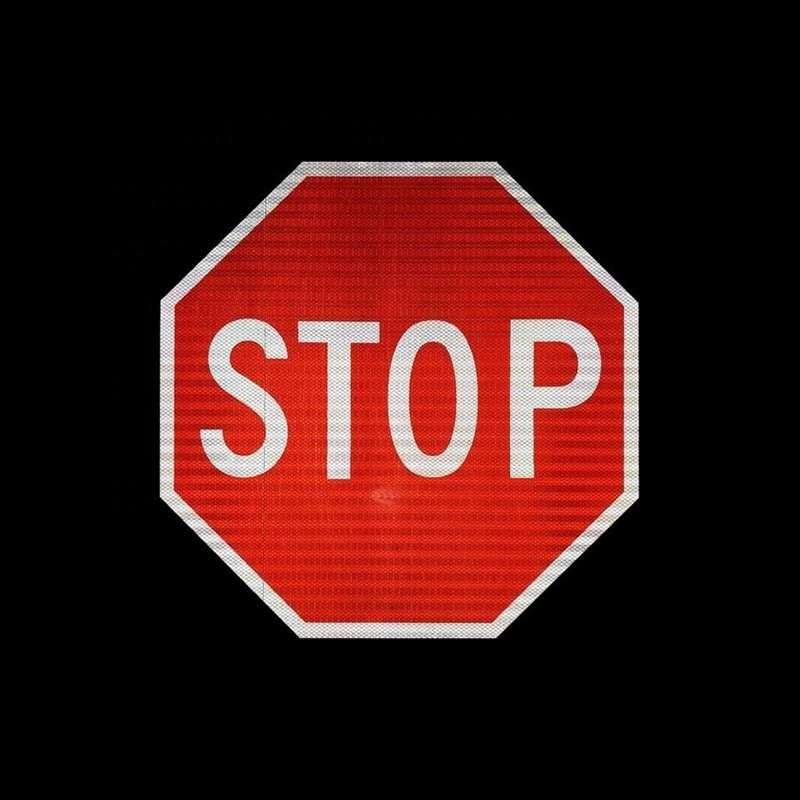 Red and white reflective octagonal STOP sign against a dark background