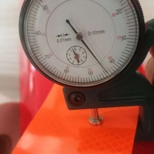 Orange prismatic reflective material close-up with thickness gauge