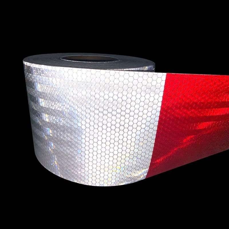 Wide red and white honeycomb reflective tape illuminated on a dark background