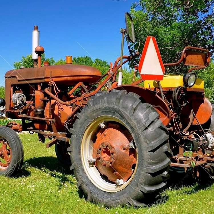 Triangular slow-moving vehicle marker mounted behind a tractor seat